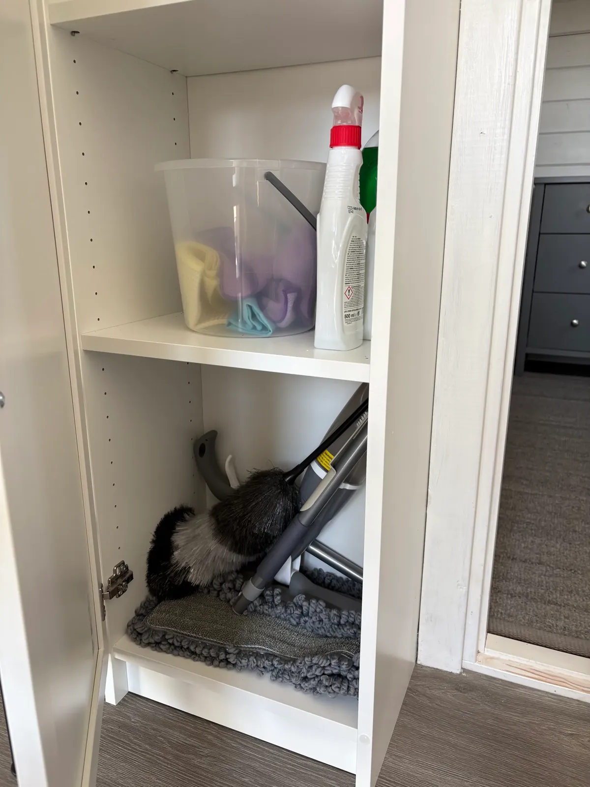 Cleaning cupboard under the stairs with cloths, detergents, duster and mop.